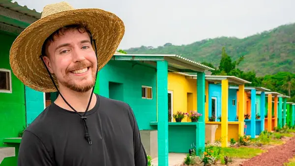 MrBeast wearing a straw hat in front of colorful houses in Peru.